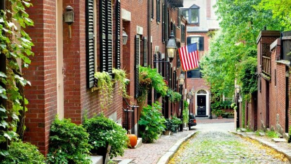 Histórica calle adoquinada de Beacon Hill en Boston con casas adosadas de ladrillo y la bandera de EE.UU. - ponte en contacto con Gavagan Law, abogado de Boston especializado en lesiones personales